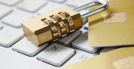 A gold lock and credit cards sit on a white keyboard. 