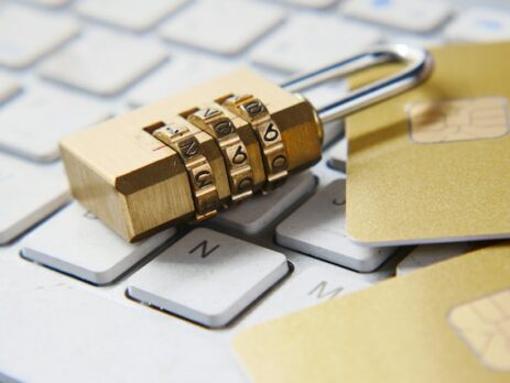 A gold lock and credit cards sit on a white keyboard. 