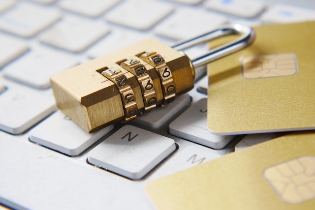 A gold lock and credit cards sit on a white keyboard. 