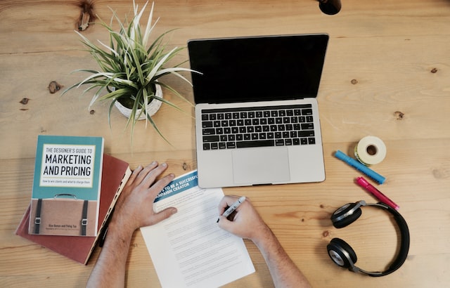 A computer on a desk next to a marketing book.