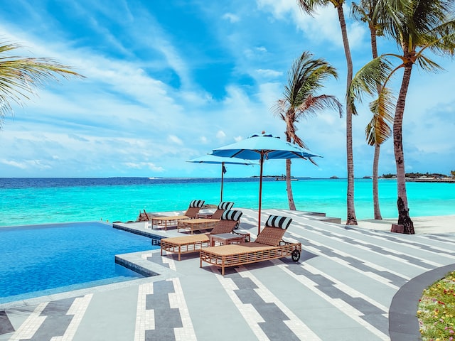 Chairs sit on a deck by the sea on a sunny day.