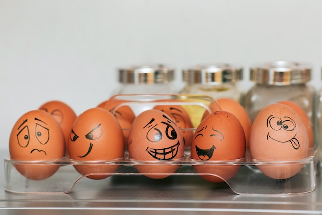 Eggs in a carton with faces drawn on them. 