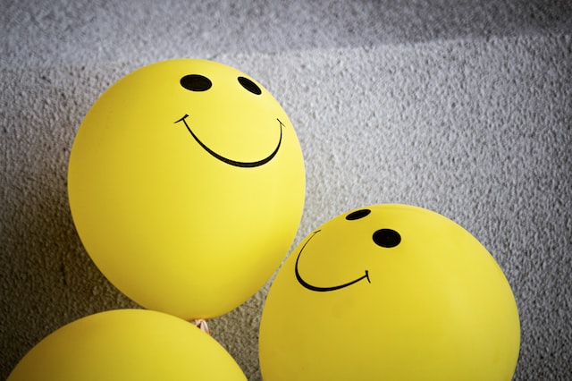 Three yellow smiley face balloons. 