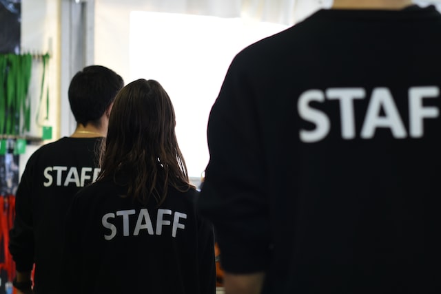 Three people in black shirts with Staff printed across the back. 
