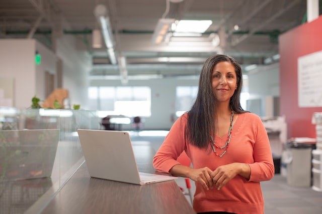 A woman stands at a counter with a laptop on it.
