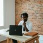 A man works at a laptop at his desk in an office. 