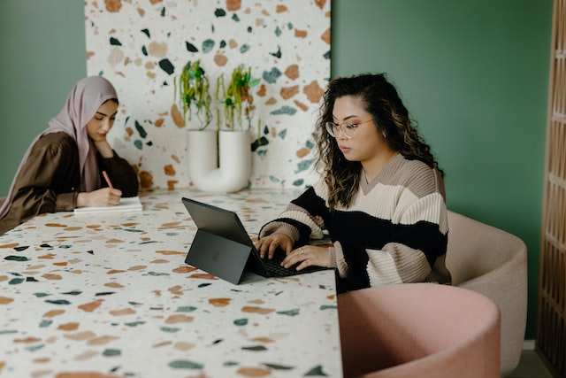 Two women work remotely at a table.