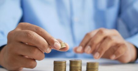 A man in a blue shirt stacks coins on a table. 