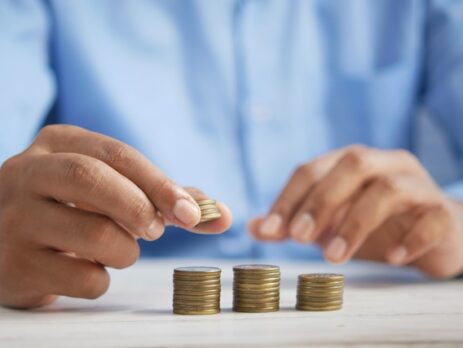 A man in a blue shirt stacks coins on a table. 