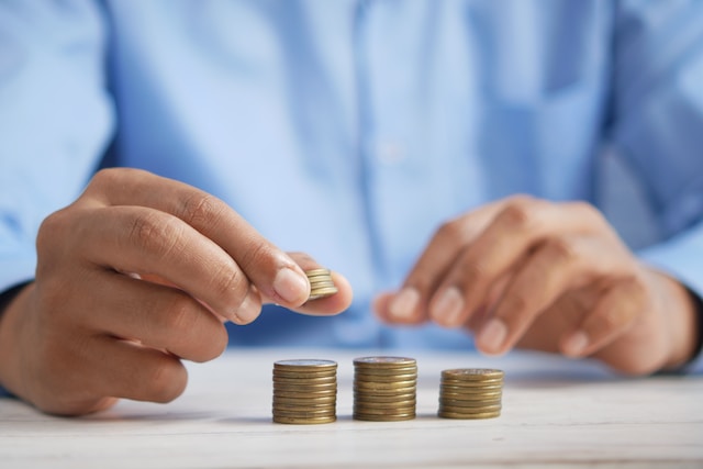 A man in a blue shirt stacks coins on a table. 