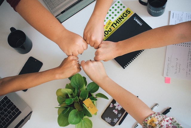 A team puts their hands in the middle of a circle in fists.