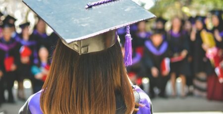 A college graduate stands with her back to the camera. 