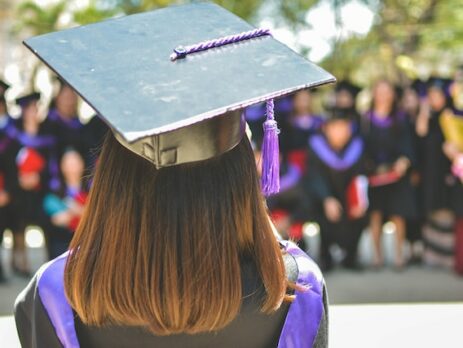 A college graduate stands with her back to the camera. 