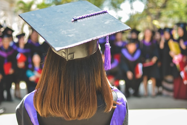 A college graduate stands with her back to the camera. 