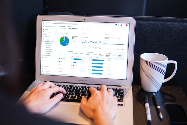 An individual works on a laptop screen that has a pie chart and other data information.
