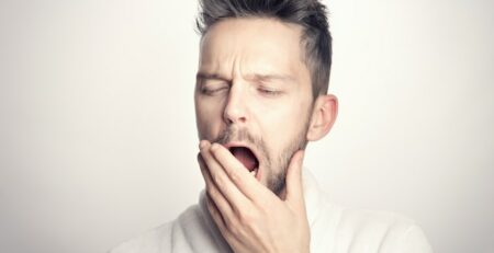 A man with light skin and dark hair yawns. 