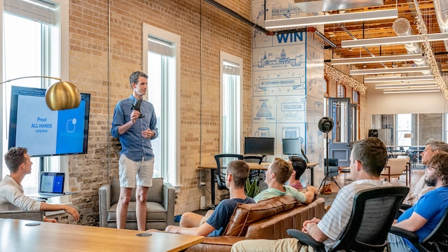 A man gives a seminar to a bunch of employees about a product. 