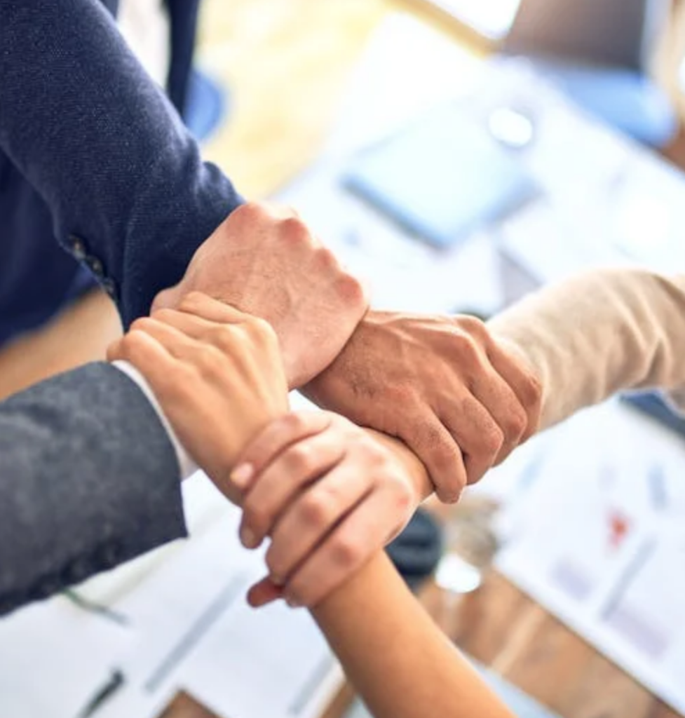 Workplace colleagues holding each other’s hands.