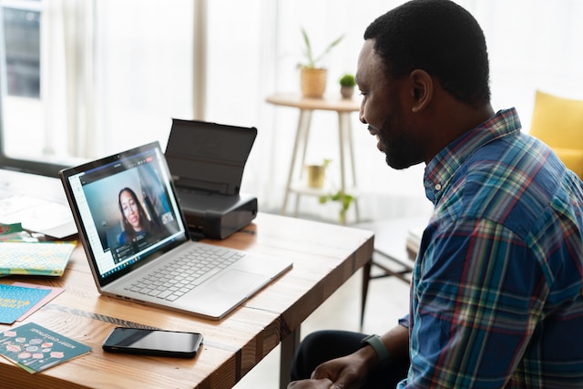 A man has a video interview with a woman on a laptop screen.