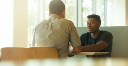 Two men sit at a table for an interview. 