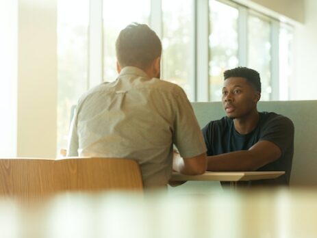 Two men sit at a table for an interview. 