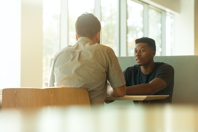 Two men sit at a table for an interview. 