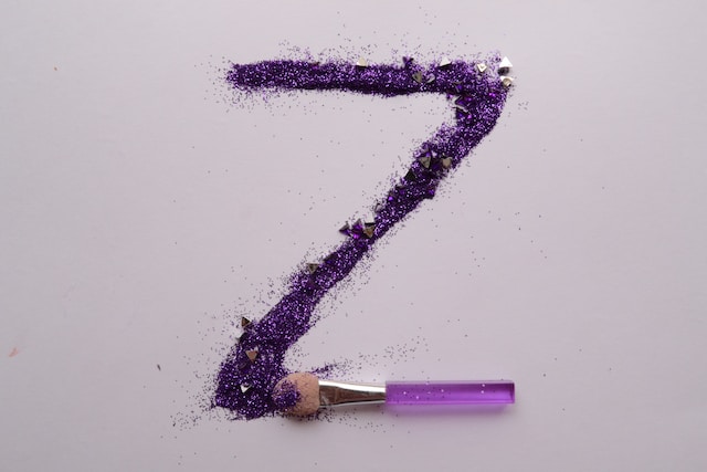 A large letter Z is made out of purple glitter using a brush. 