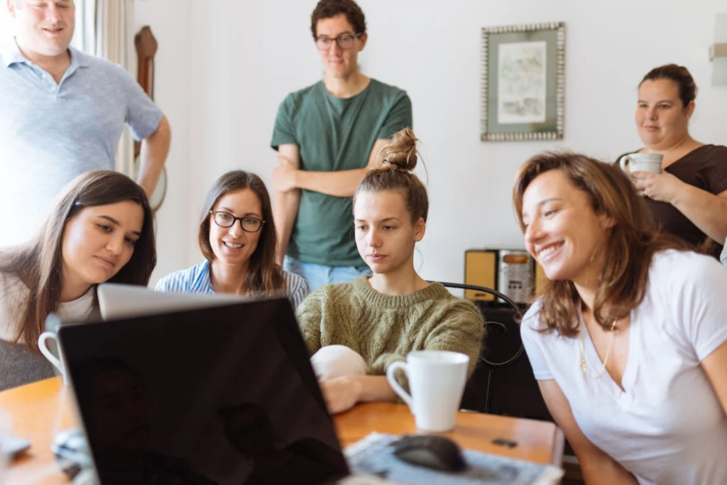 Men and women sitting around a desk looking at a computer.