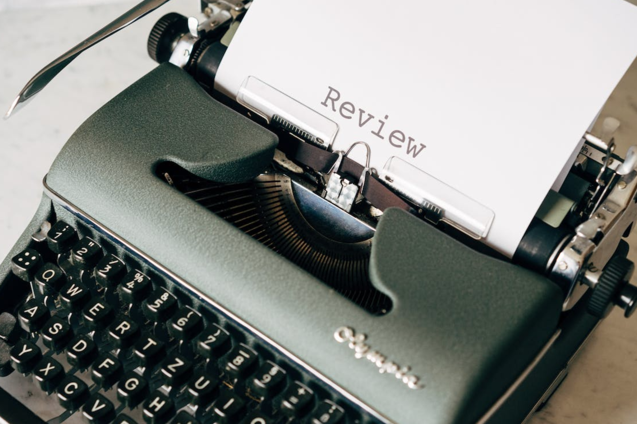 A paper with the word “Review” written on it on a typewriter.
