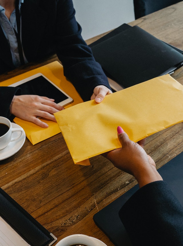 Boss giving out a yellow envelop to a female worker