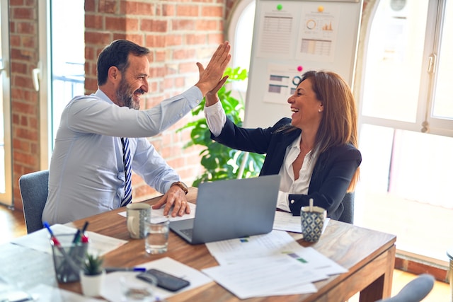 Two co-workers celebration in an office together.