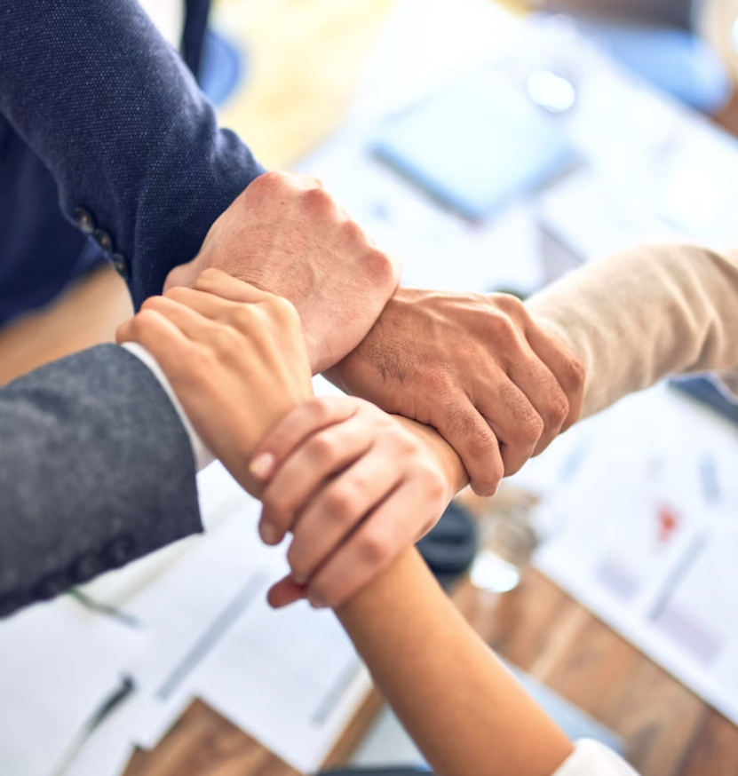 Workers holding hands in an office.