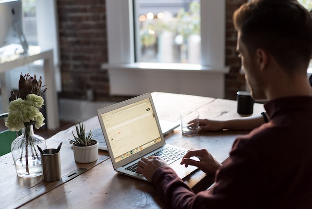 A man works on a laptop while sitting at a table.