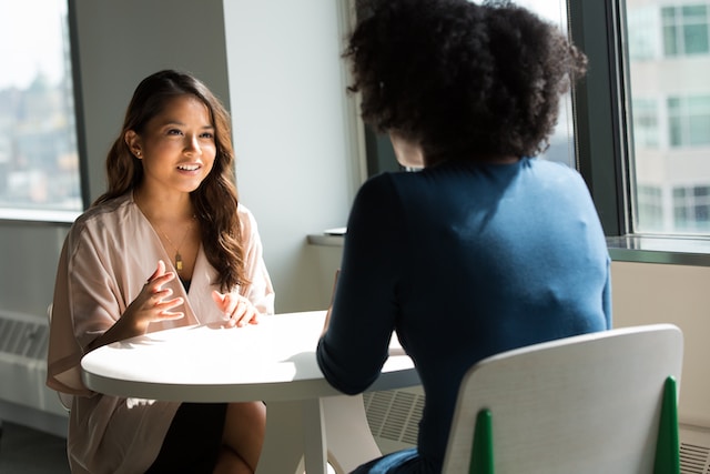 Two women have a meeting at a desk.