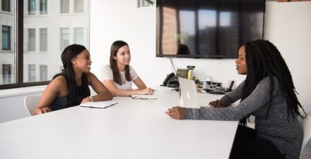 Three women sitting at an office desk.