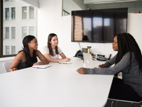 Three women sitting at an office desk.