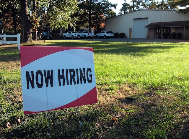 A “Now hiring” sign in front of a building.