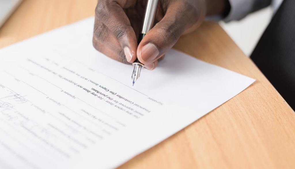 man signing a paper contract