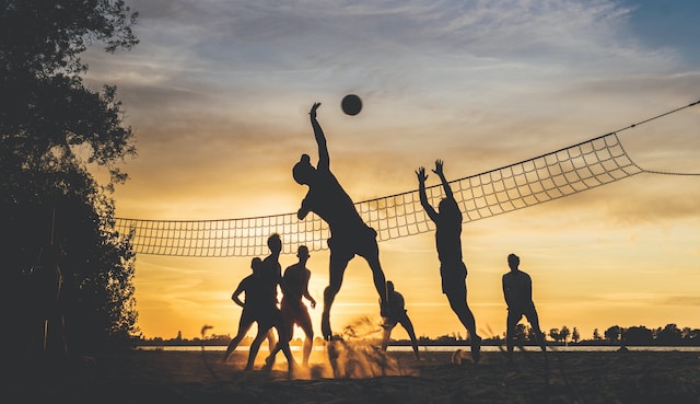 A group of people playing volleyball outside.