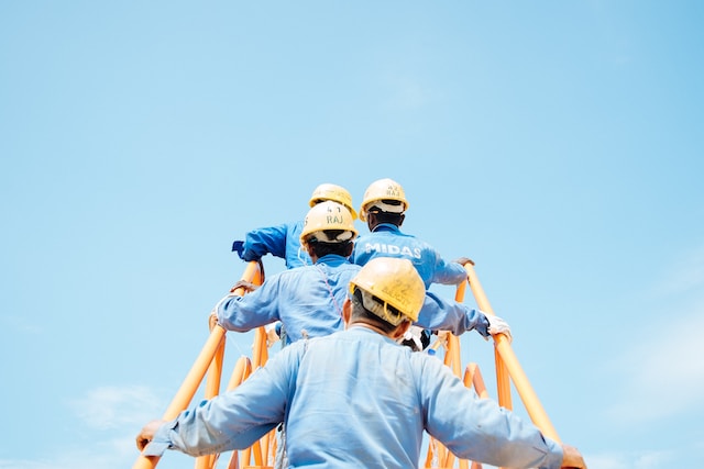 men in hardhats walking up ladder