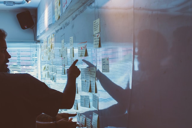 A man pointing at sticky notes on a whiteboard.