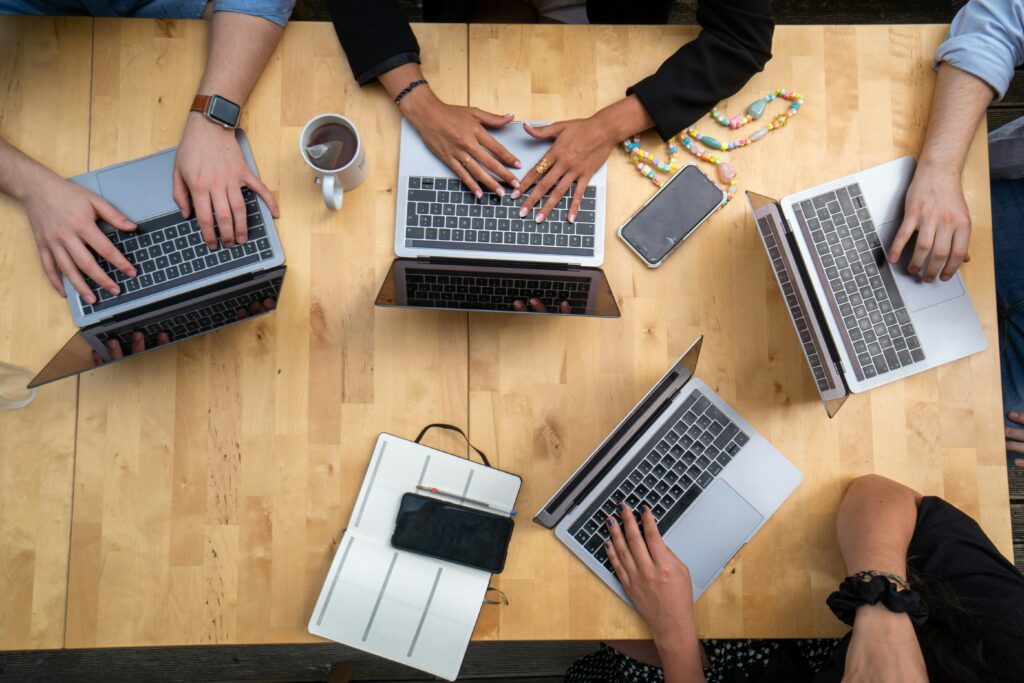 A group of individuals sitting around with laptops in front of them.