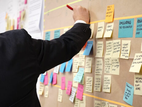 A man writes on sticky notes in an office.