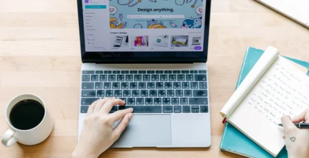 A person using a laptop and writing simultaneously