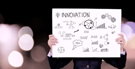 A person holds up a sign that says: “Innovation.”