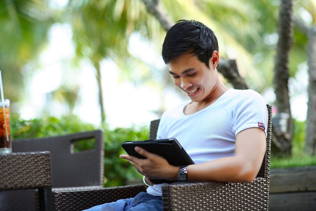 Man smiling while working on tablet.
