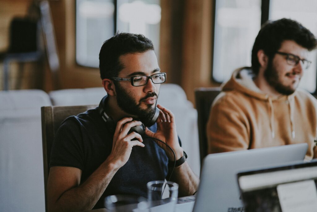 man wearing glasses and headphones next to smiling man
