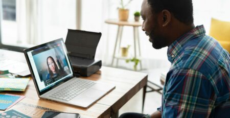 Man in blue and white checkered dress shirt using macbook pro