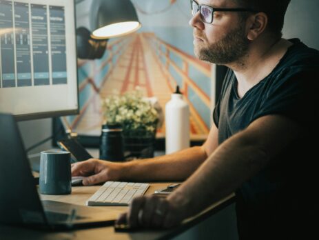 Man with a black tshirt and black glasses using the computer