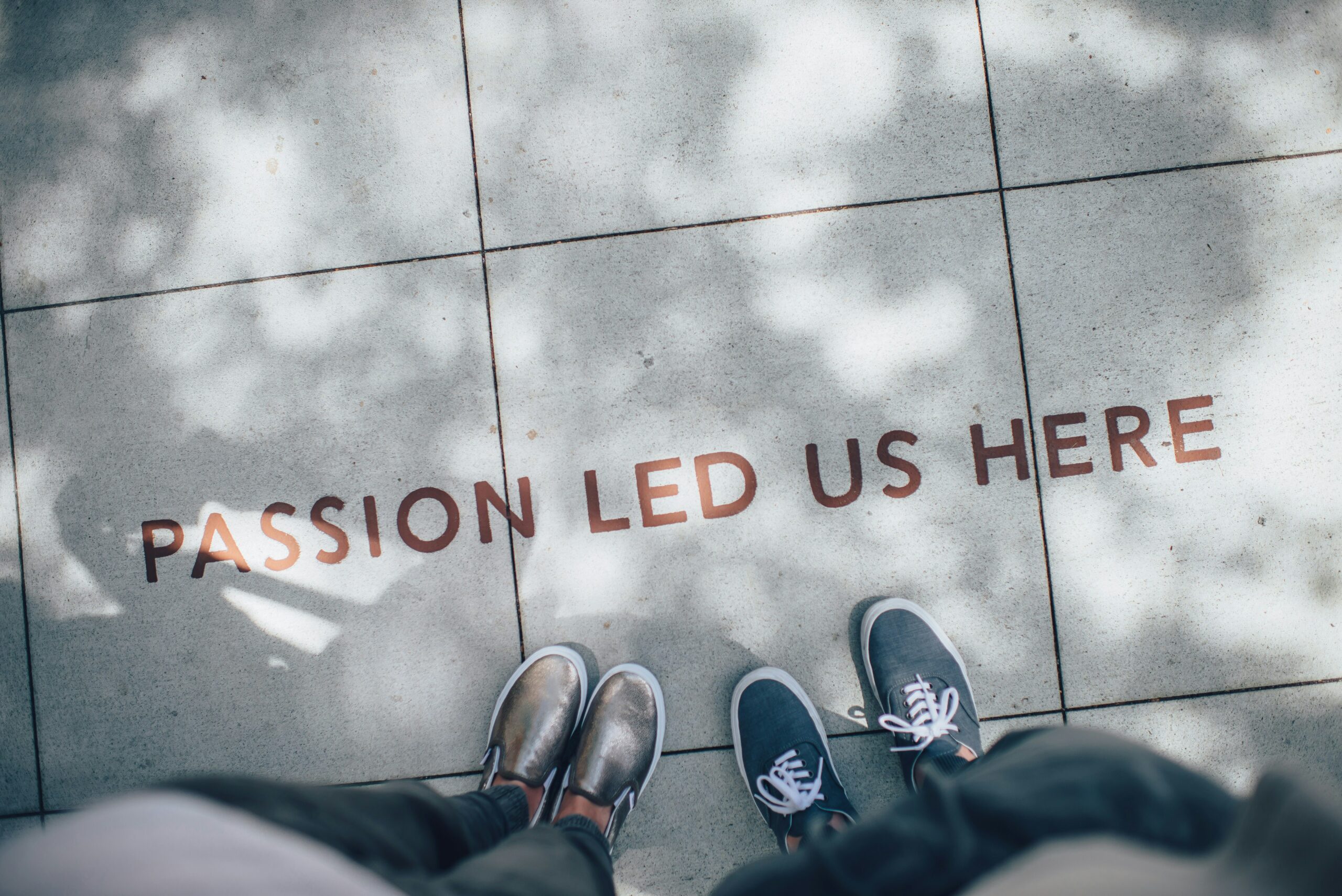 Two people's feet showing a quote on the floor and their shoes.